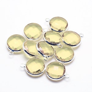 May include: Ten round, faceted, light yellow gemstone pendants with silver jump rings. The pendants are approximately 1 inch in diameter.