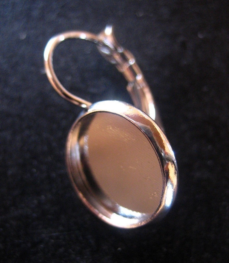 May include: Silver earring with a round, flat, silver bezel for a cameo or other embellishment.