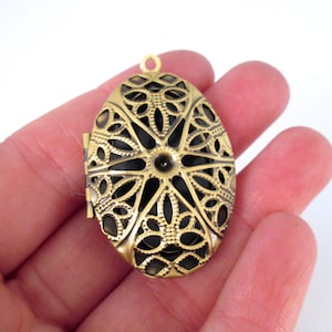 May include: A gold-toned oval locket with a filigree design. The locket has a hinged opening and a loop for attaching a chain.