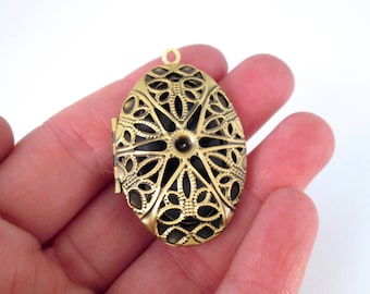 May include: A gold-toned oval locket with a filigree design. The locket has a hinged opening and a loop for attaching a chain.