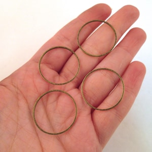May include: Four gold-colored metal rings of different sizes, lying on a hand.