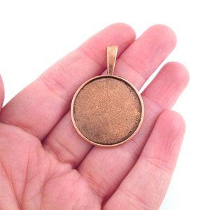 May include: A round copper pendant with a smooth, slightly textured surface. The pendant has a loop at the top for attaching a chain.