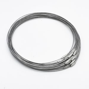 May include: A set of 10 silver-toned cable chain necklaces. The chains are made of a thin, flexible cable and have a simple, modern design.