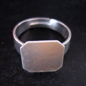 May include: A silver ring with a blank, octagonal-shaped top. The ring is adjustable and can be personalized.