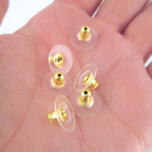 May include: Six gold-toned earring backs with clear plastic backing. The backs are designed to hold earrings in place.