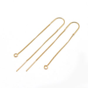 May include: A pair of gold chain earrings with a simple, curved design. The earrings are long and dangle, with a small loop at the top for attaching to an earring post.