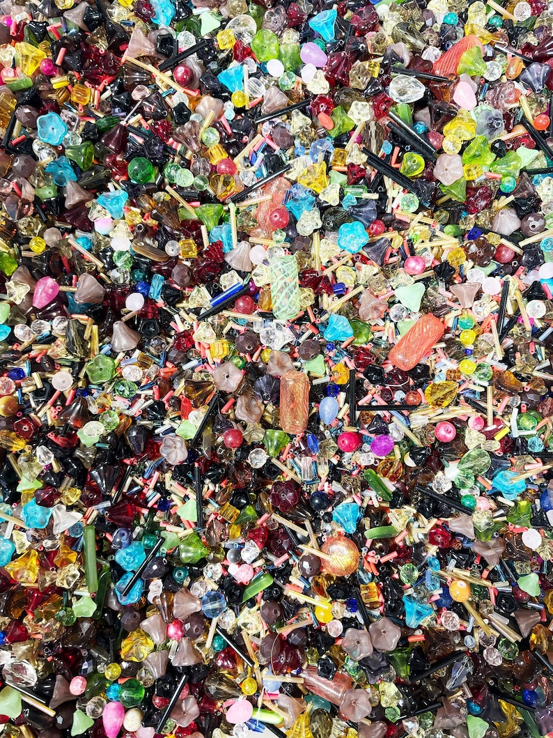 May include: A large assortment of colorful glass beads in various shapes and sizes. The beads are a mix of clear, opaque, and iridescent colors, including red, blue, green, yellow, and purple. The beads are perfect for jewelry making, crafts, and home decor.