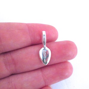 May include: Silver teardrop shaped pendant bail with a loop at the top.
