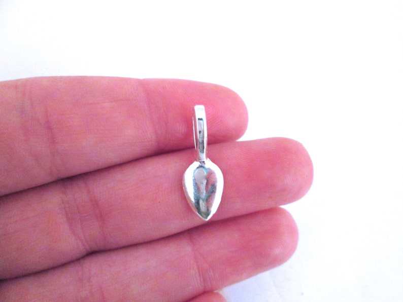May include: Silver teardrop shaped pendant bail with a loop at the top.