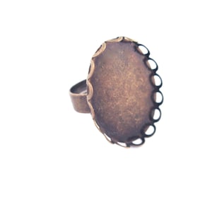 May include: A bronze ring with a round, scalloped bezel. The bezel is empty and ready to be filled with a cabochon.