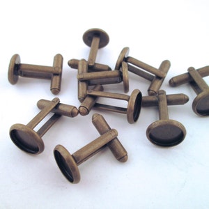 May include: A set of eight antique brass cufflinks with round glass cabochon settings. The cufflinks are perfect for adding a touch of vintage style to any outfit.