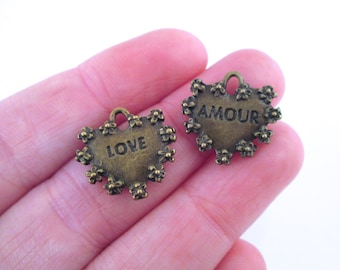 May include: Two antique gold heart-shaped charms with floral details. One charm says "LOVE" and the other says "AMOUR".
