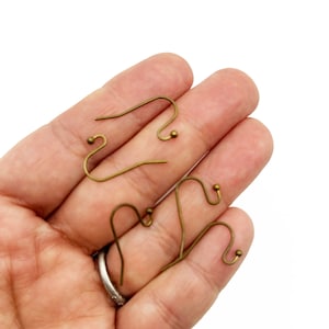 May include: Four gold-toned earring hooks with a small ball at the end of each hook.