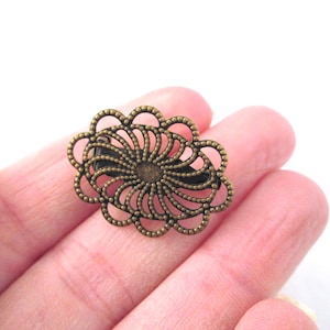 May include: A bronze-colored metal hair clip with a decorative, openwork design resembling a flower.