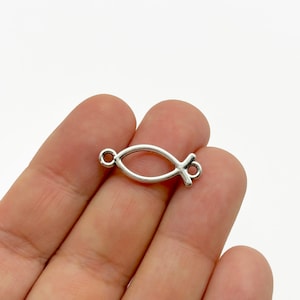 Può includere: Ciondolo in metallo argentato a forma di pesce con un anello ad ogni estremità.