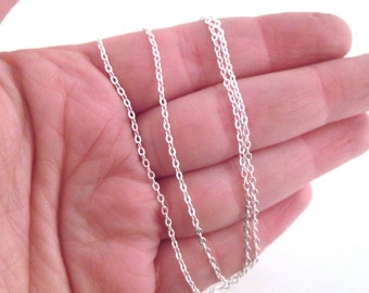May include: A silver chain necklace with three strands of chain. The chain is delicate and has a smooth finish.