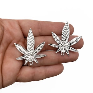 May include: Two silver-toned marijuana leaf charms with a loop at the bottom for attaching to jewelry or other crafts.