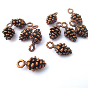 May include: A collection of 10 copper-toned pine cone charms with a loop for attaching to jewellery or crafts.