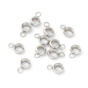 May include: A selection of shiny, silver metal jewellery components. Each component features a rounded, hollow body with a small loop attached. The components are scattered on a white surface, perfect for crafting.
