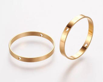 May include: Two gold-colored metal rings with a smooth finish. Each ring has three small holes.