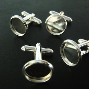 May include: Four silver cufflinks with round, clear glass insets. The cufflinks are designed to hold a small image or design.