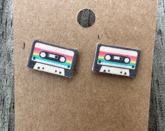 May include: A pair of earrings featuring a retro cassette tape design. The earrings are made of a white material with a rainbow colored design on the cassette tape.