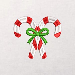 May include: Embroidered design of two candy canes with red and white stripes, joined by a green bow. The candy canes have red tips and a diamond pattern on the lower portion. Festive holiday theme.