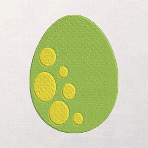 Puede incluir: Huevo verde bordado con manchas circulares amarillas. El huevo es de color verde claro y las manchas son de un amarillo brillante. El diseño es probablemente para un parche o aplique, adecuado para proyectos temáticos de Pascua o dinosaurios.