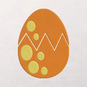 Pode incluir: Design de ovo laranja bordado com detalhes circulares amarelos e um padrão em zigue-zague branco. O ovo está rachado, revelando o interior. O design é provavelmente para artesanato com tema de Páscoa ou primavera.