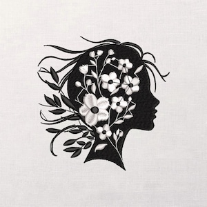 May include: Black silhouette of a person's profile, filled with white flowers and leaves. The design is embroidered on a light-colored fabric, creating a contrast between the dark profile and the delicate floral details.