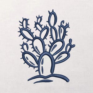 May include: A navy blue embroidered cactus design on a white background. The cactus features a stylized shape with multiple pads and sharp spines. The embroidery is detailed, creating a textured appearance.