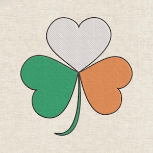 May include: Embroidered shamrock with a heart-shaped top leaf and three heart-shaped leaves in green, white, and orange, outlined in black. The design is on a beige fabric background.
