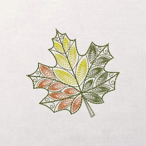 Könnte beinhalten: Gesticktes Ahornblatt-Design in Grün, Gelb und Orange auf weißem Hintergrund. Das Blatt weist detaillierte Stickereien und ein stilisiertes, dekoratives Muster auf, ideal für herbstliche Bastelarbeiten oder Dekorationen.