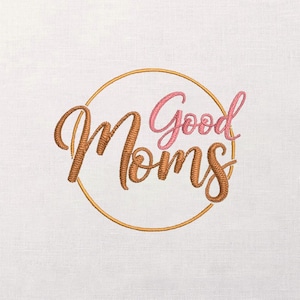 May include: Embroidered design featuring the words "Good Moms" in a cursive script. The word "Moms" is in a brown color, while "Good" is in pink. The text is inside a gold circle, set against a white background.