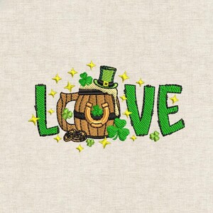 Może przedstawiać: Haftowany wzór z napisem "LOVE" w kolorze zielonym, w tematyce Dnia Świętego Patryka. Zawiera drewniany kufel do piwa, zielony kapelusz krasnoludka, koniczyny, precle, podkowę i żółte gwiazdy na beżowym tle.