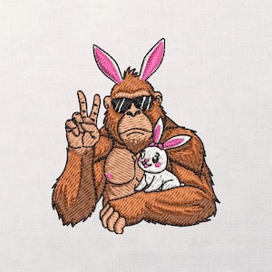 May include: Embroidered design featuring a brown gorilla wearing sunglasses and bunny ears, giving a peace sign. The gorilla is holding a white bunny with pink ears. The design is on a white background.
