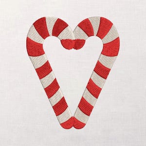 May include: Embroidered design of two candy canes forming a heart shape. The candy canes are red and white striped, with a detailed stitch pattern. The background is a plain white fabric.