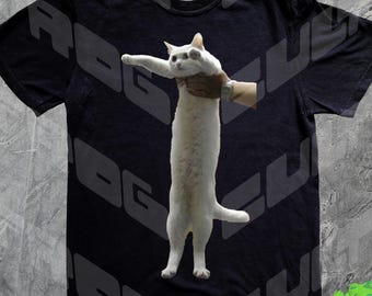 Puede incluir: Camiseta negra con un diseño gris repetido de las letras «ROG» y un gato blanco sujetado en posición vertical. El gato tiene las patas delanteras extendidas. Un logotipo verde con el texto «FROG CULT» está en la esquina inferior derecha.