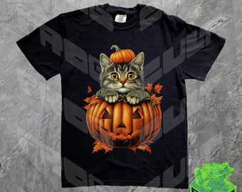 May include: A black t-shirt with a graphic of a tabby cat sitting inside a carved orange pumpkin. The cat is looking at the viewer with its paws on the rim of the pumpkin. The pumpkin has a carved face with a triangle nose and a wide grin.