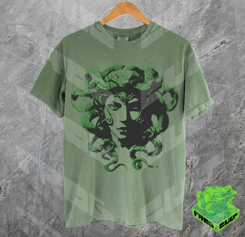 May include: A green t-shirt featuring a black and green graphic print of Medusa, a mythical Greek figure with snakes for hair.