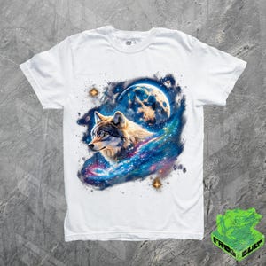 Puede incluir: Camiseta blanca con un gr&aacute;fico de un lobo aullando a la luna en un entorno de galaxia. El lobo es gris y blanco, y la galaxia es azul, p&uacute;rpura y rosa.
