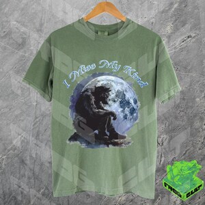 May include: A green t-shirt with a wolf howling at the moon graphic. The text "I Miss My Kind" is printed on the shirt.