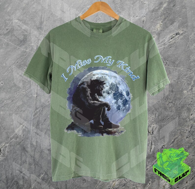 May include: A green t-shirt with a wolf howling at the moon graphic. The text "I Miss My Kind" is printed on the shirt.