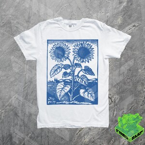 May include: White t-shirt with a blue vintage print of two sunflowers. The print is in a rectangular frame and features a stylized design of the sunflowers with leaves and stems.