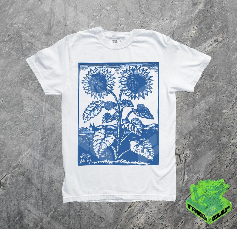 May include: White t-shirt with a blue vintage print of two sunflowers. The print is in a rectangular frame and features a stylized design of the sunflowers with leaves and stems.
