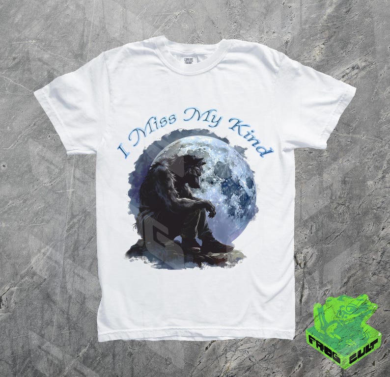 May include: White t-shirt with a black werewolf silhouette sitting under a blue moon. The text "I Miss My Kind" is printed in blue on the shirt.