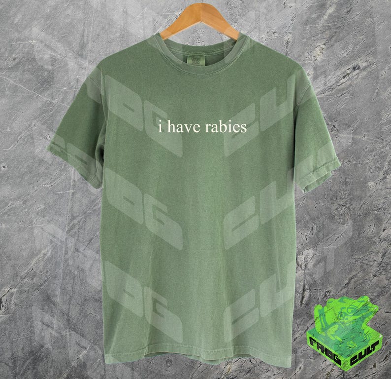 Może przedstawiać: Zielony T-shirt z nadrukiem "i have rabies" z przodu.