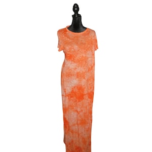以下が含まれることがあります： オレンジ色のタイダイマキシドレス。半袖と丸いネックラインが特徴です。黒いマネキンに着せられています。生地は質感があり、ドレスは床まで届く長さです。