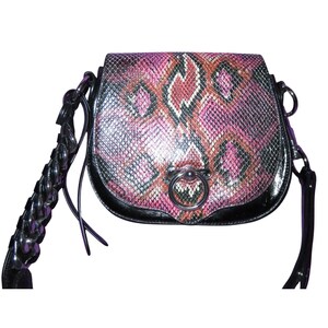 Może przedstawiać: Mała, okrągła torebka z wzorem skóry węża w odcieniach różu, czerni i brązu. Torebka ma czarne skórzane wykończenie i srebrne metalowe zapięcie w kształcie pierścienia. Pasek jest czarny i pleciony.