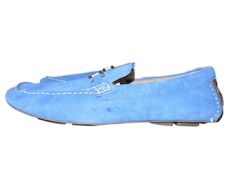 May include: A pair of light blue suede loafers with white stitching and a brown heel. The shoes have a classic design with a slip-on style and a rubber sole. The loafers are a size 10.